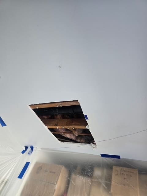 Single small rectangular access opening cut between garage ceiling joists