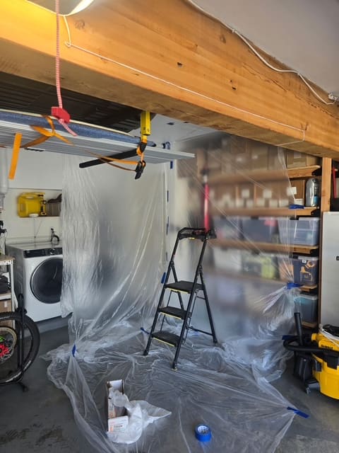 Plastic containment sheeting protecting garage shelving and appliances during leak detection