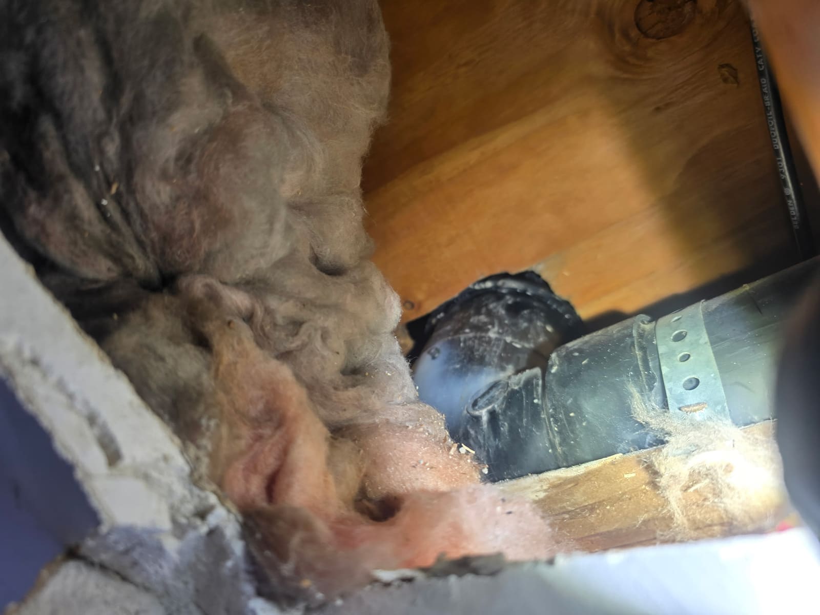 ABS drain line exposed inside the garage ceiling joist bay during leak detection