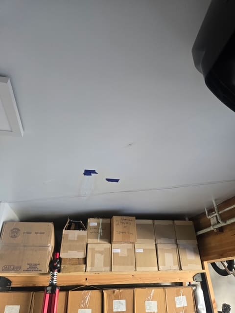 Painter’s tape marking the water stained garage ceiling below an upstairs bathroom leak
