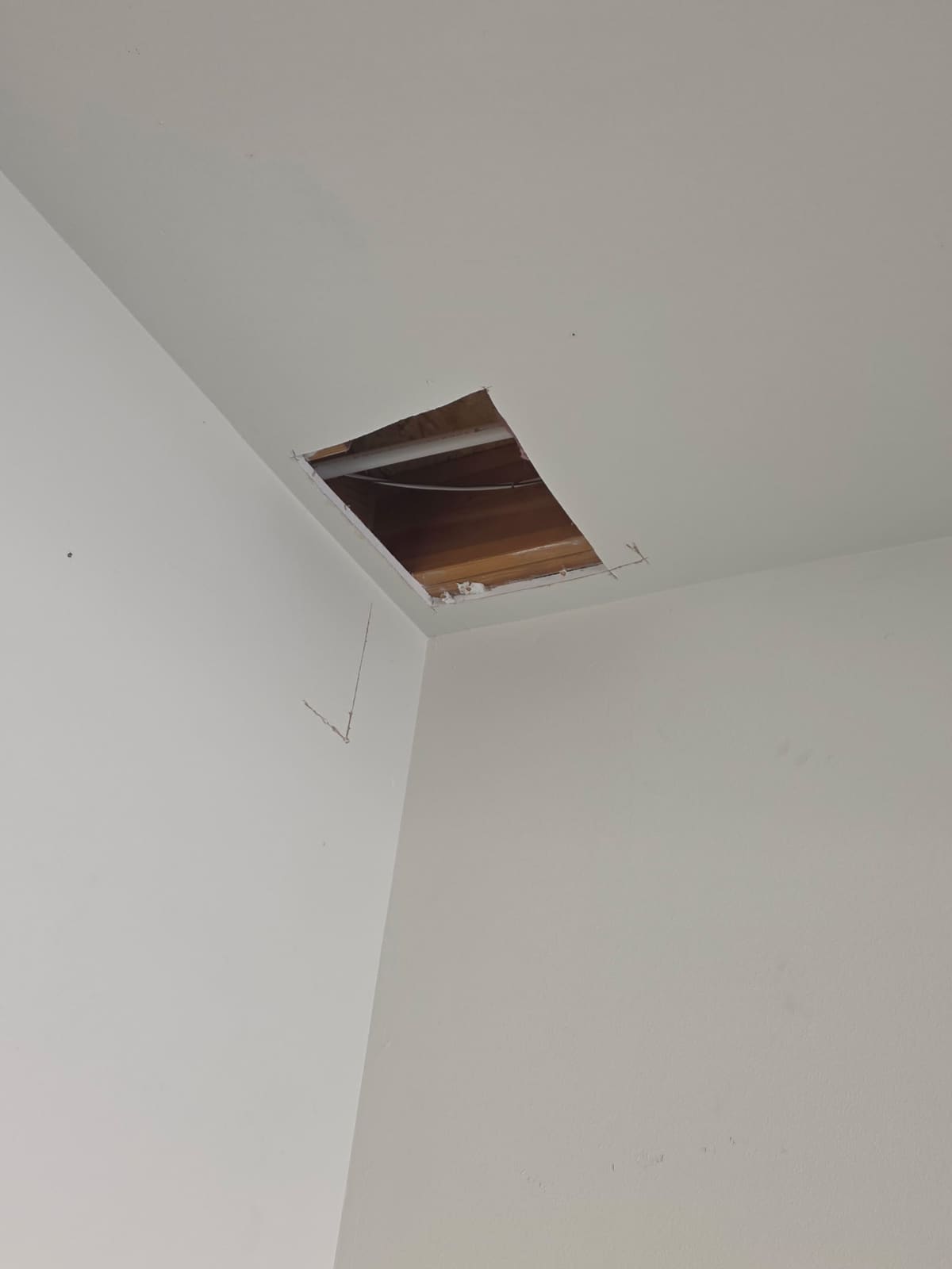 Clean rectangular ceiling access opening with the new rerouted water line visible