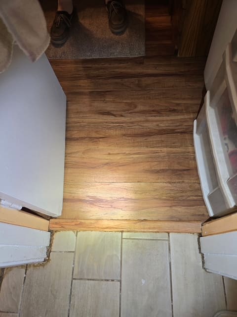 Laminate flooring lifting at a bathroom threshold from hidden water damage in San Bernardino